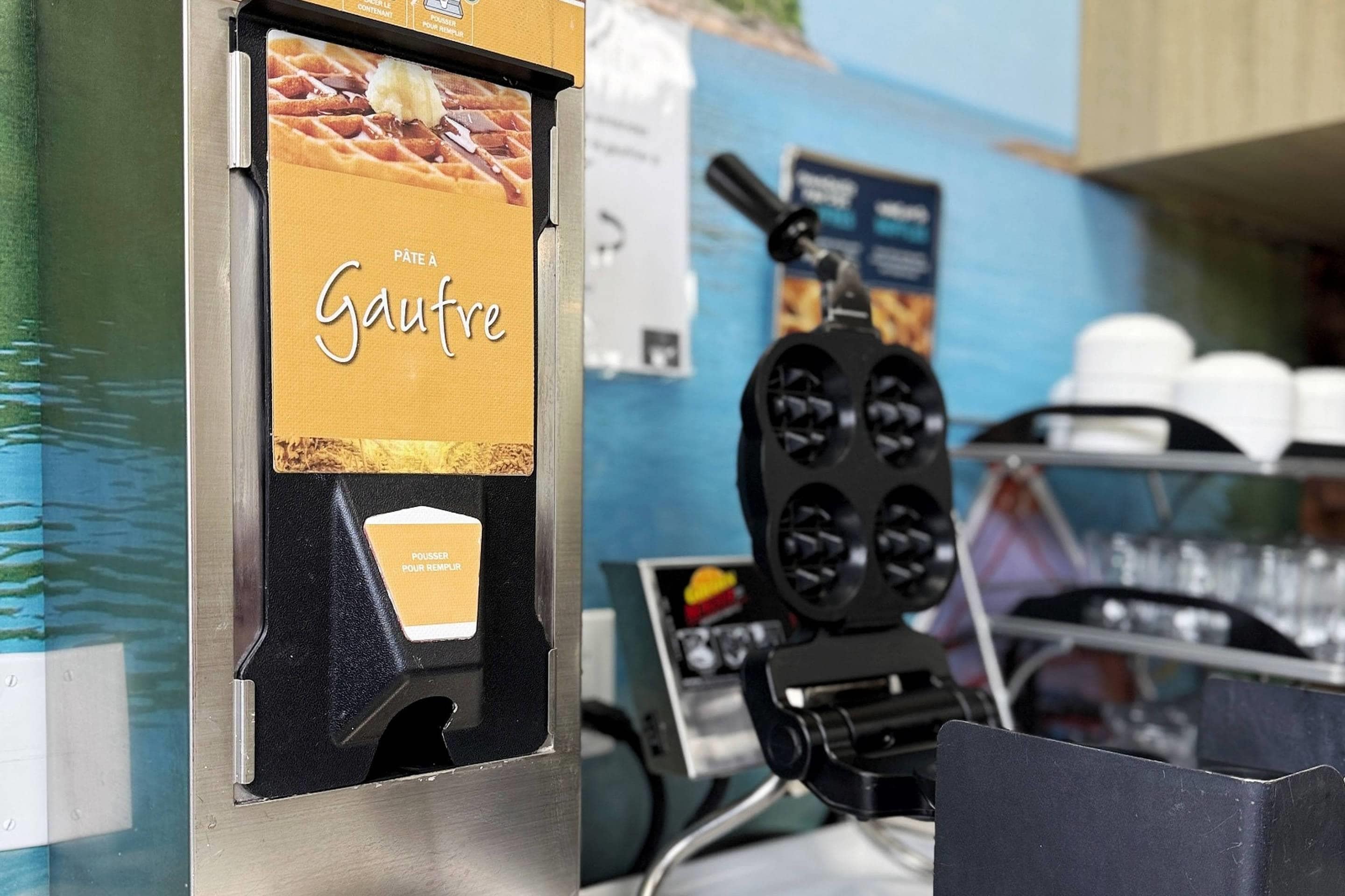Una máquina para hacer gofres con un letrero que dice 'Pâte à Gaufre' y un botón etiquetado 'POUSSER POUR REMPLIR'.