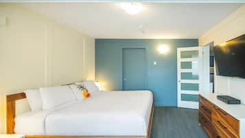 Een slaapkamer met een bed, een dressoir, een televisie en een deur met geëtste glaspanelen.