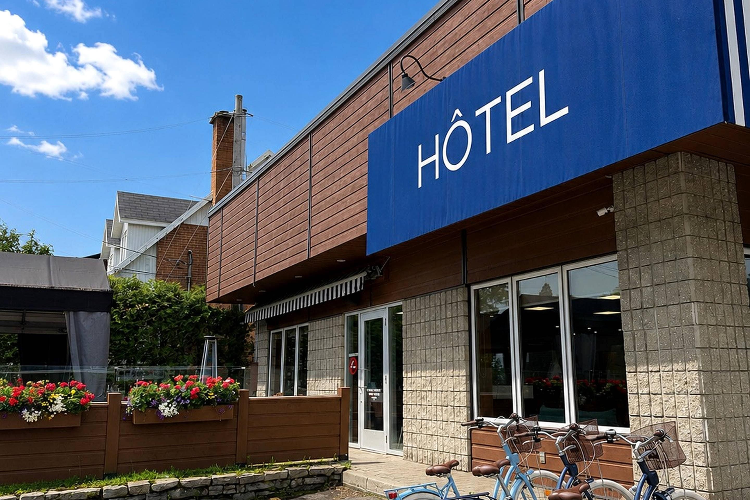 Un hotel con un llamativo letrero azul, fachada de madera y un pilar de piedra.