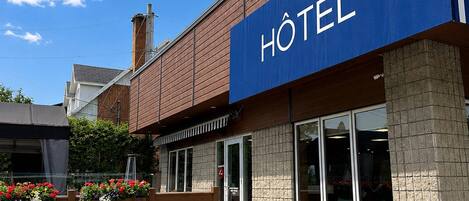 Un hotel con un llamativo letrero azul, fachada de madera y un pilar de piedra.