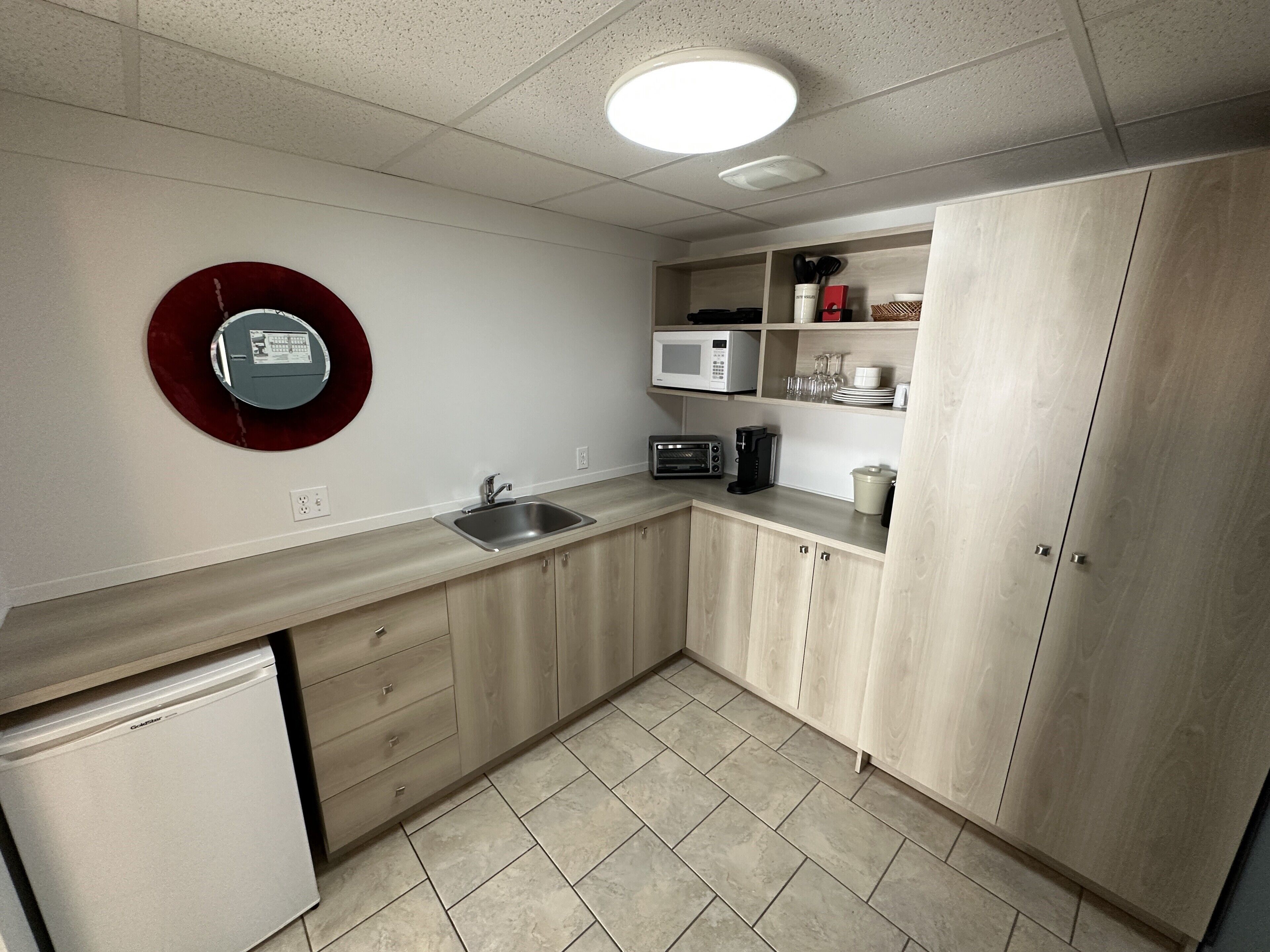 A kitchen with a microwave, toaster, sink, and cabinets.