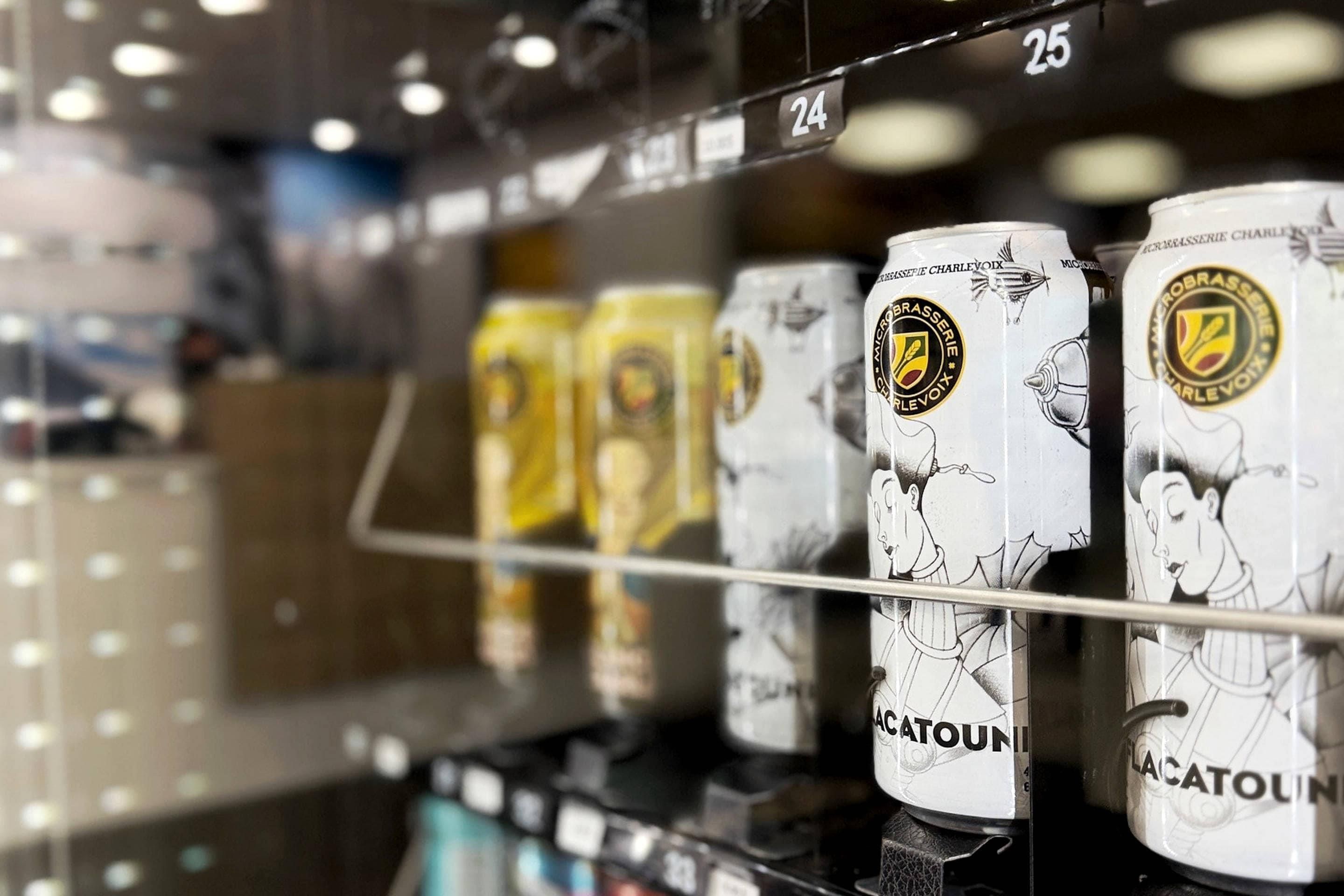 A refrigerated display case with cans of beer, each labeled with a brand name and a logo.