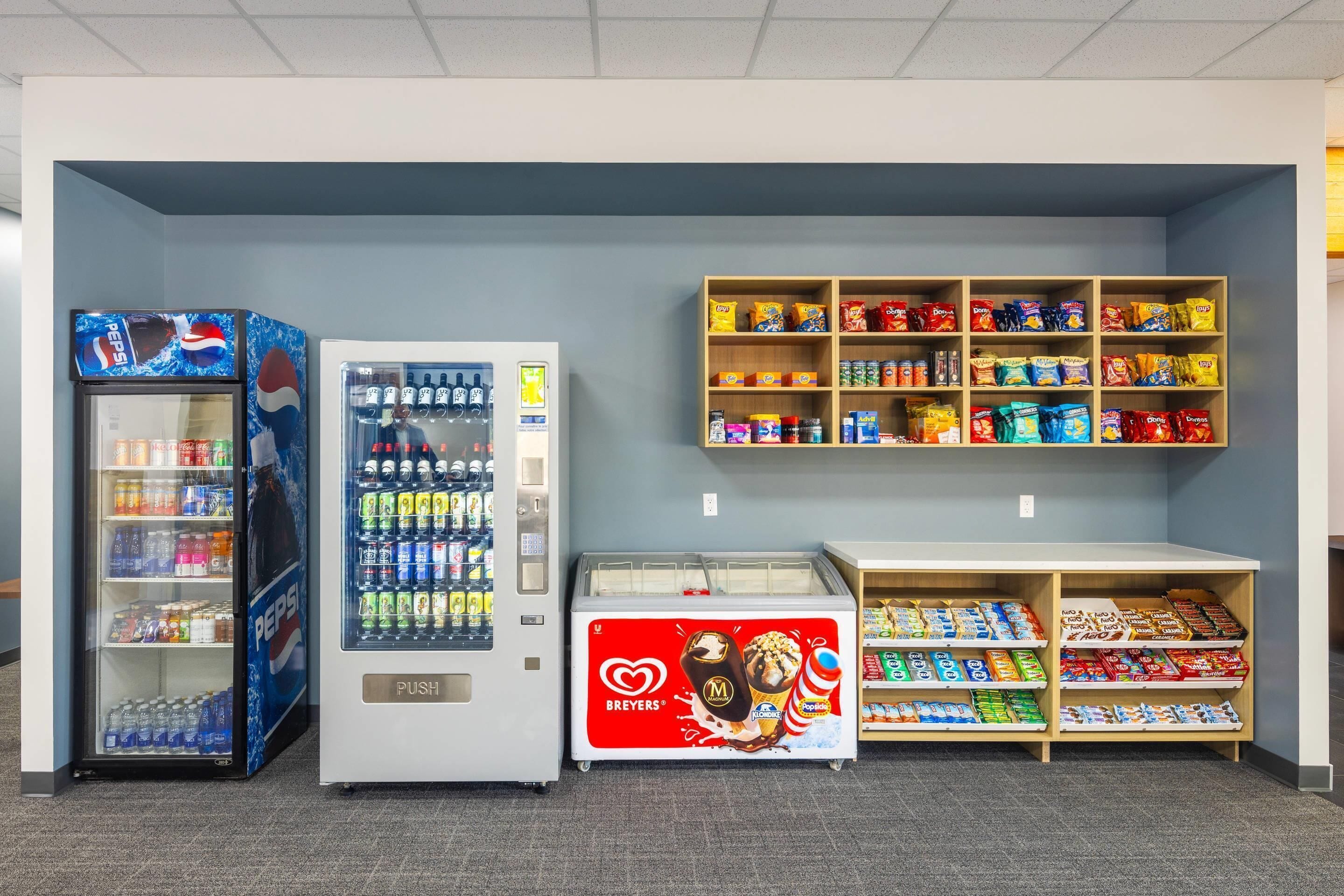 Vending machines, a refrigerated display, and snack shelves in a commercial setting.