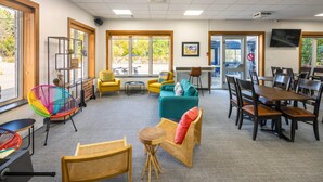 A spacious room with a large window, a television, and a variety of seating options including chairs and sofas. - Clarion Pointe La Malbaie (La Malbaie)