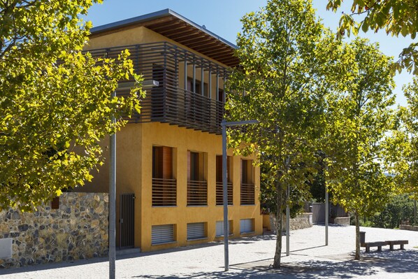 Un edificio moderno con fachada de piedra, varias ventanas y techo plano.