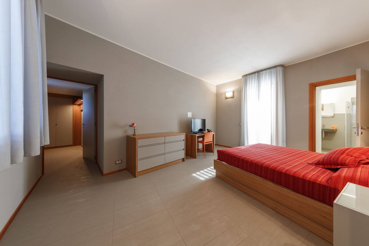 Un dormitorio con cama, escritorio y armario.