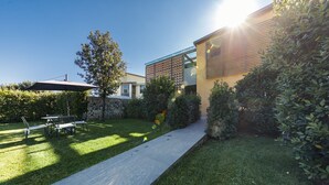 Een modern huis met een bestraat terras, een eethoek en een verzorgd gazon.