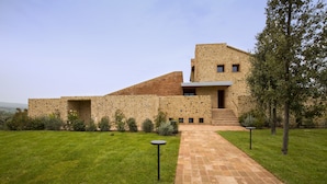 Un bâtiment moderne avec une façade en pierre, une partie en briques et une entrée pavée.