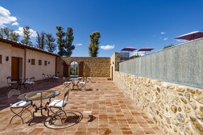 Un patio al aire libre con muros de piedra, mesas y sillas.
