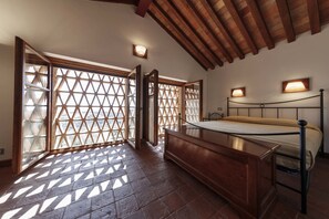 Un dormitorio con estructura de cama de madera, una mesita de noche y un ventanal con diseño de celosía.