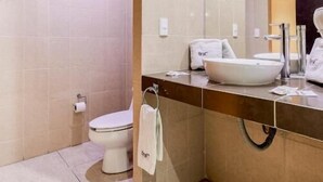 A modern bathroom with a toilet, sink, and large mirror.