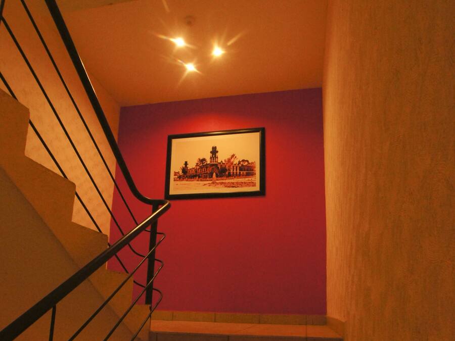 Una escalera con barandilla de metal que lleva a un rellano con un cuadro en la pared.