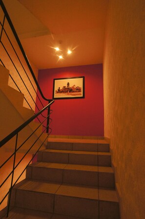 A staircase with a metal railing leading to a landing with a framed picture on the wall. - First Inn Hotel & Business (Texcoco de Mora)
