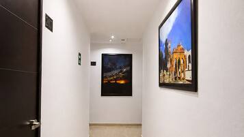 A hallway with a door labeled '207', a framed picture on the wall, and a tiled floor.