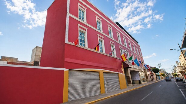 A red building with multiple windows and flags, a closed garage door, and a clear sky.