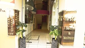 A hotel entrance with a glass door, a staircase, and potted plants. - First Inn Hotel & Business (Texcoco de Mora)