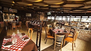 A restaurant with multiple tables set for dining, featuring checkered tablecloths and wooden chairs. - First Inn Hotel & Business (Texcoco de Mora)