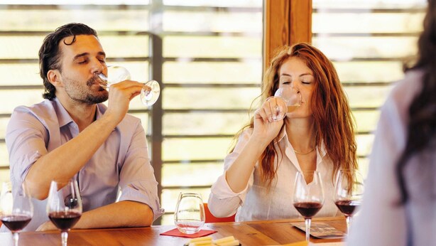 A dining area with wooden tables and chairs, large windows with blinds, and wine glasses on the table. - Wine Relais in Montecucco (Cinigiano)