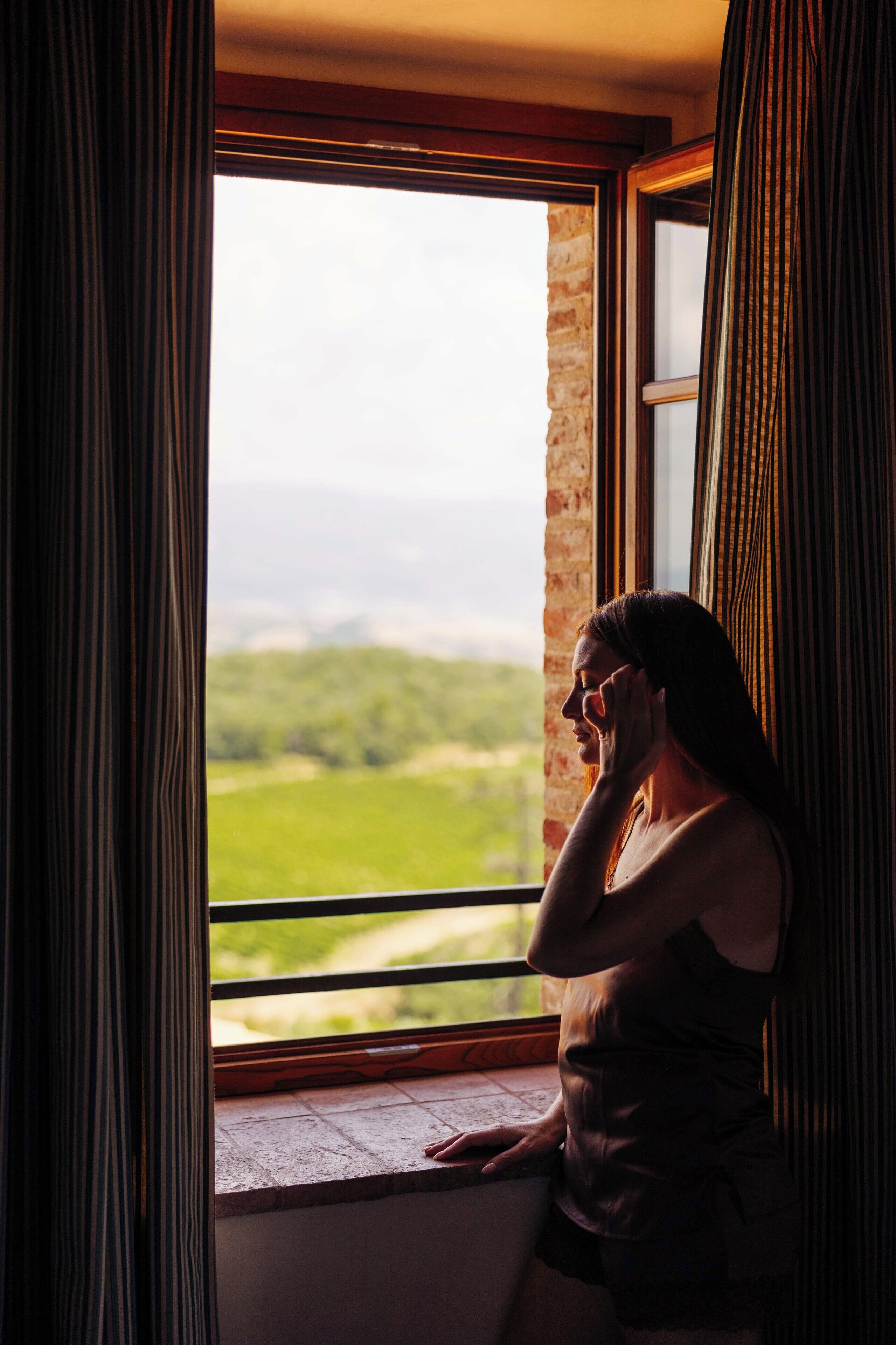 Una persona seduta vicino a una finestra con vista su un paesaggio verde.