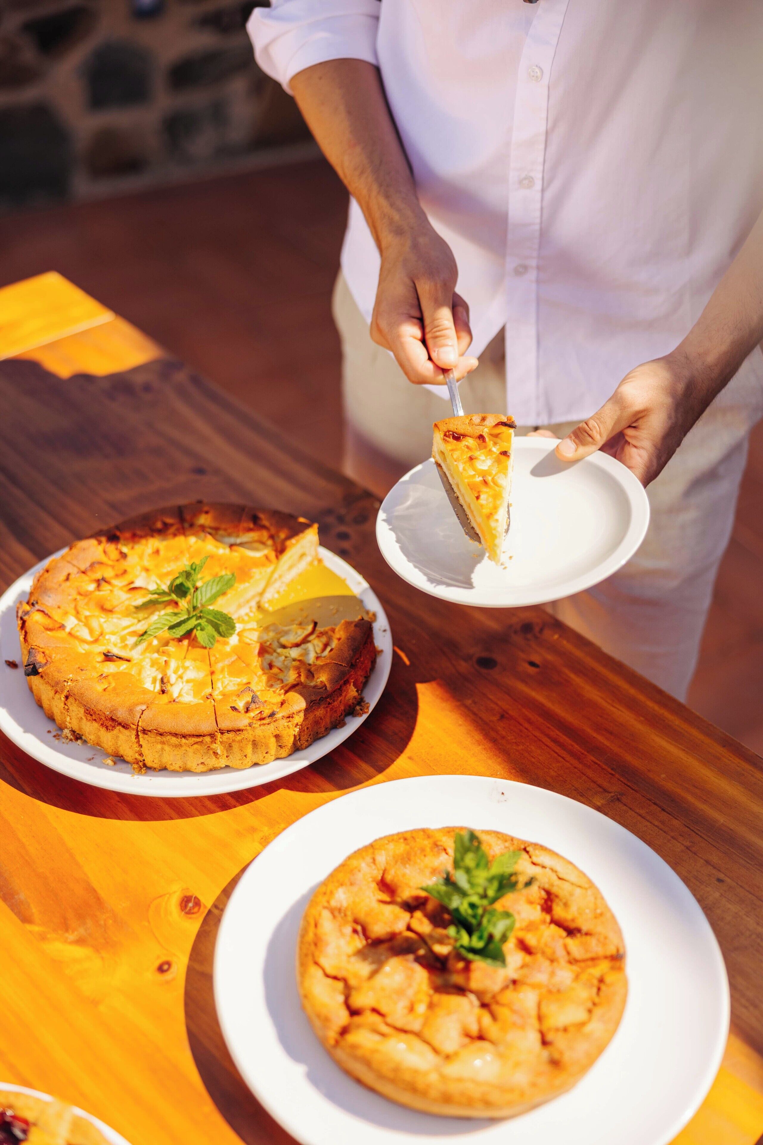 Una persona sirve una porción de pizza desde una mesa de madera.