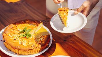 Una persona sirve una porción de pizza desde una mesa de madera.
