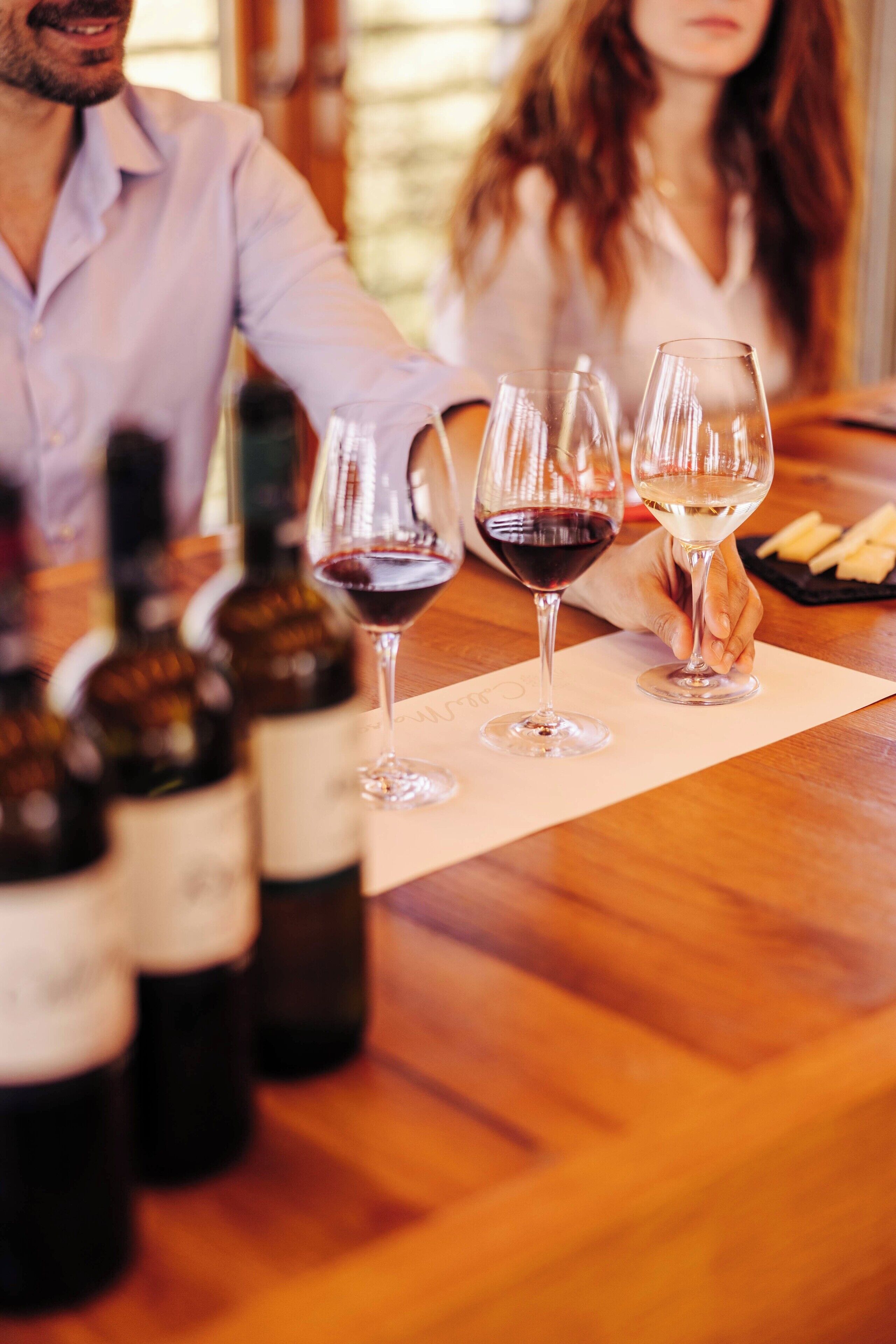 A wooden table with wine bottles and glasses, suggesting a wine tasting event.