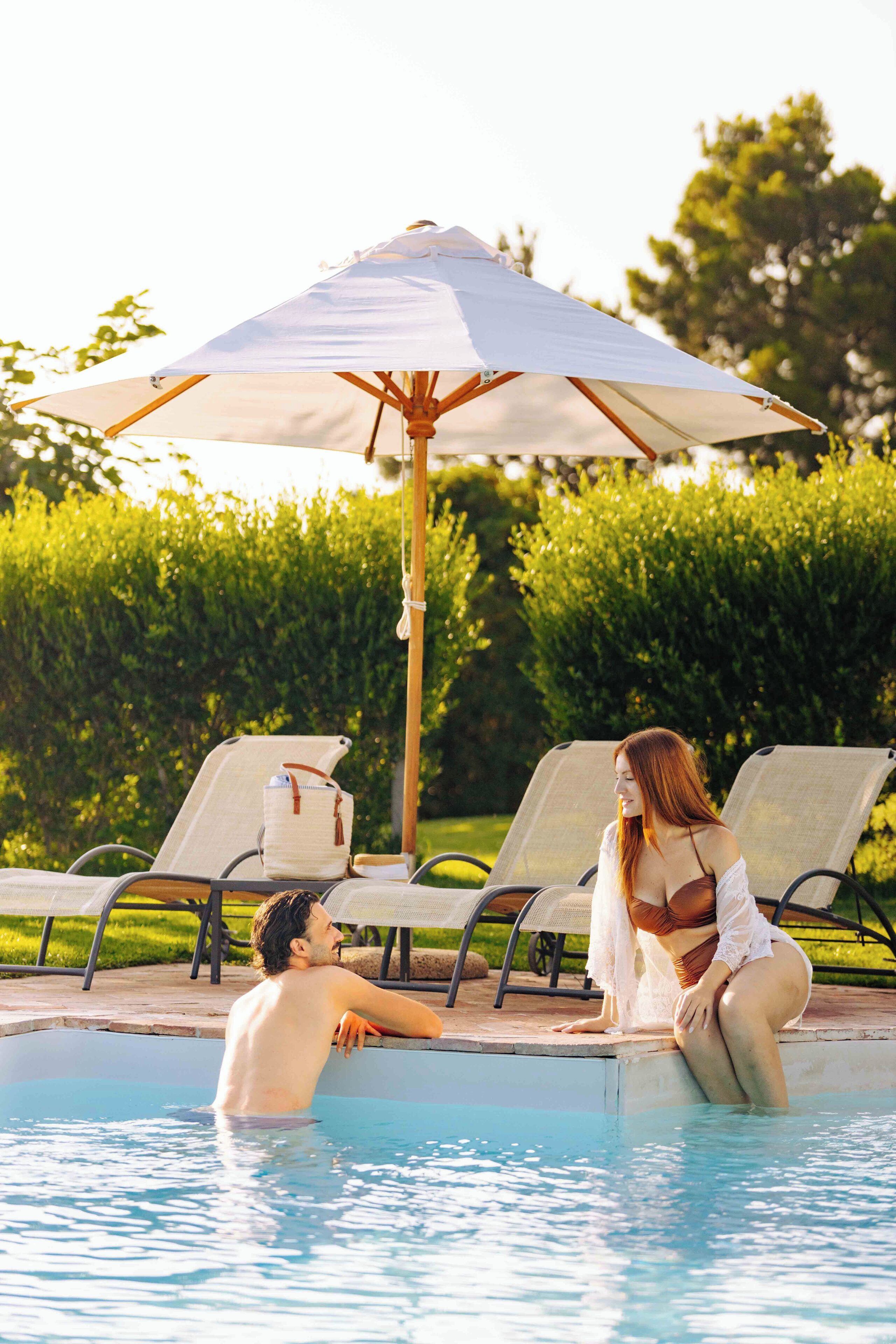 A poolside area with lounge chairs and an umbrella.
