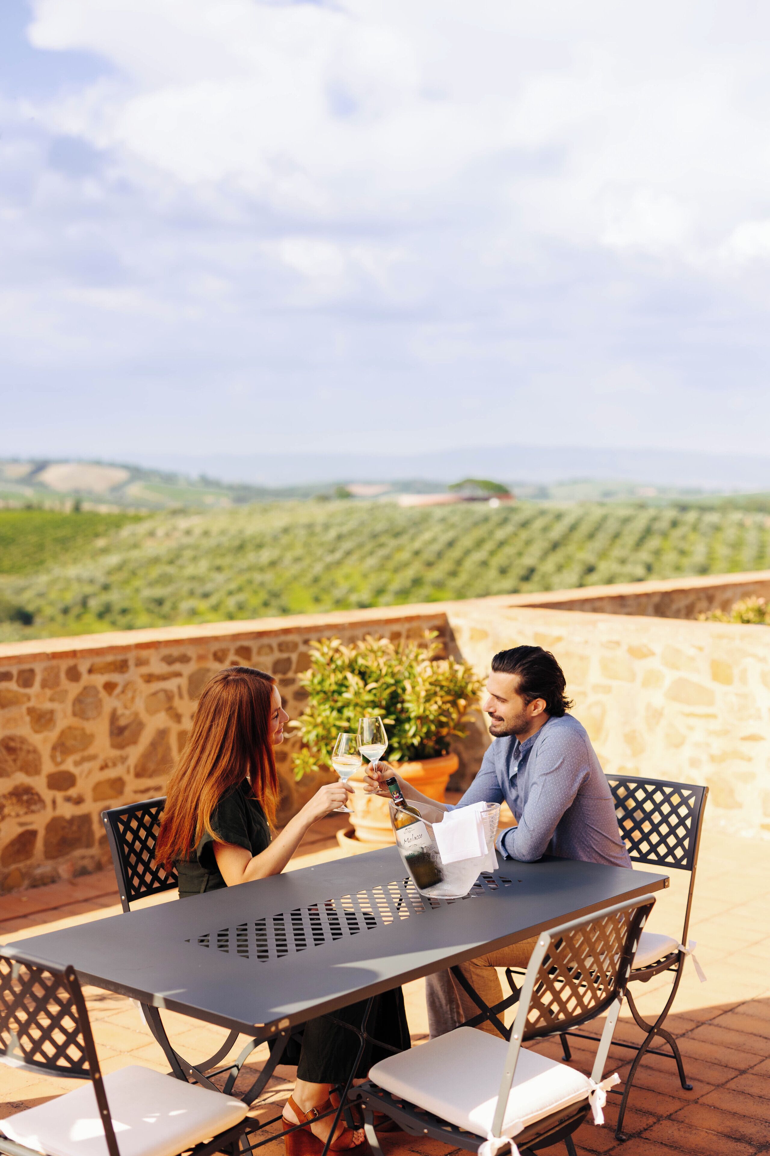 Una pareja sentada en una mesa al aire libre con vistas a viñedos.