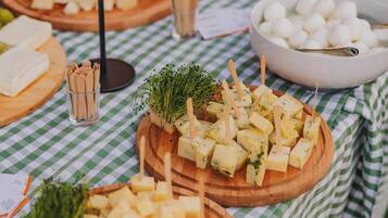 Una tabla de quesos y embutidos con diversos tipos de queso, galletas y adornos sobre un mantel a cuadros.