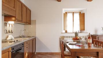 Una cucina con mobili in legno, un piano di lavoro in granito, un forno integrato e un'area pranzo con tavolo e sedie in legno.