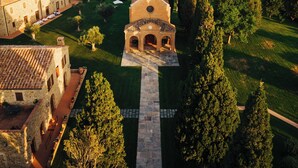 An aerial view of a historic building complex with a central tower, surrounded by lush greenery and vineyards. - Wine Relais in Montecucco (Cinigiano)