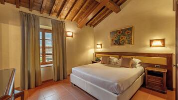 Un dormitorio con una cama grande, cabecera de madera, dos mesitas de noche y una ventana con cortinas.