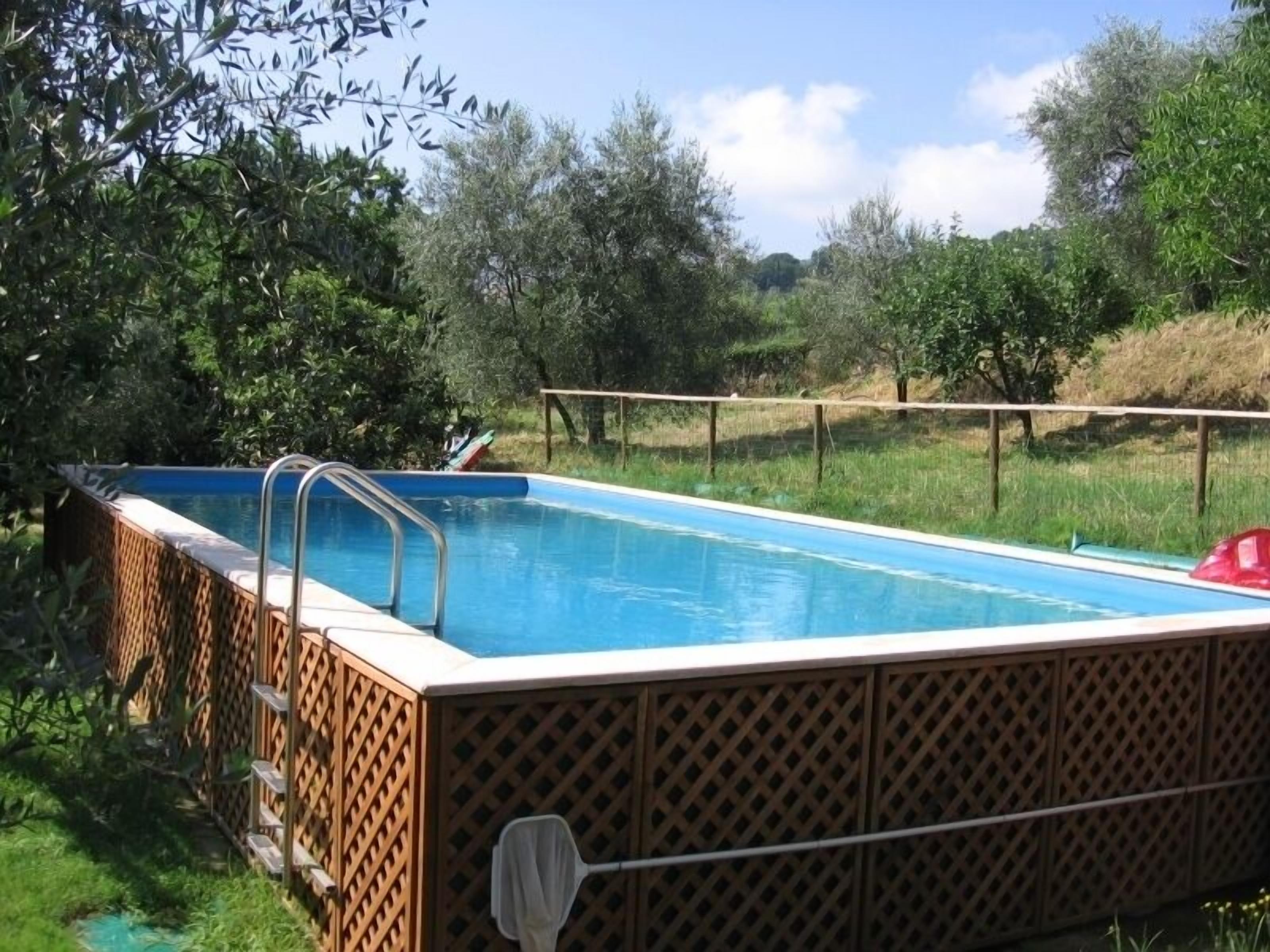 A rectangular swimming pool with a wooden lattice fence and a metal ladder.