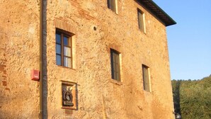 Un edificio in pietra con un portale ad arco centrale, diverse finestre e una piccola torre campanaria.