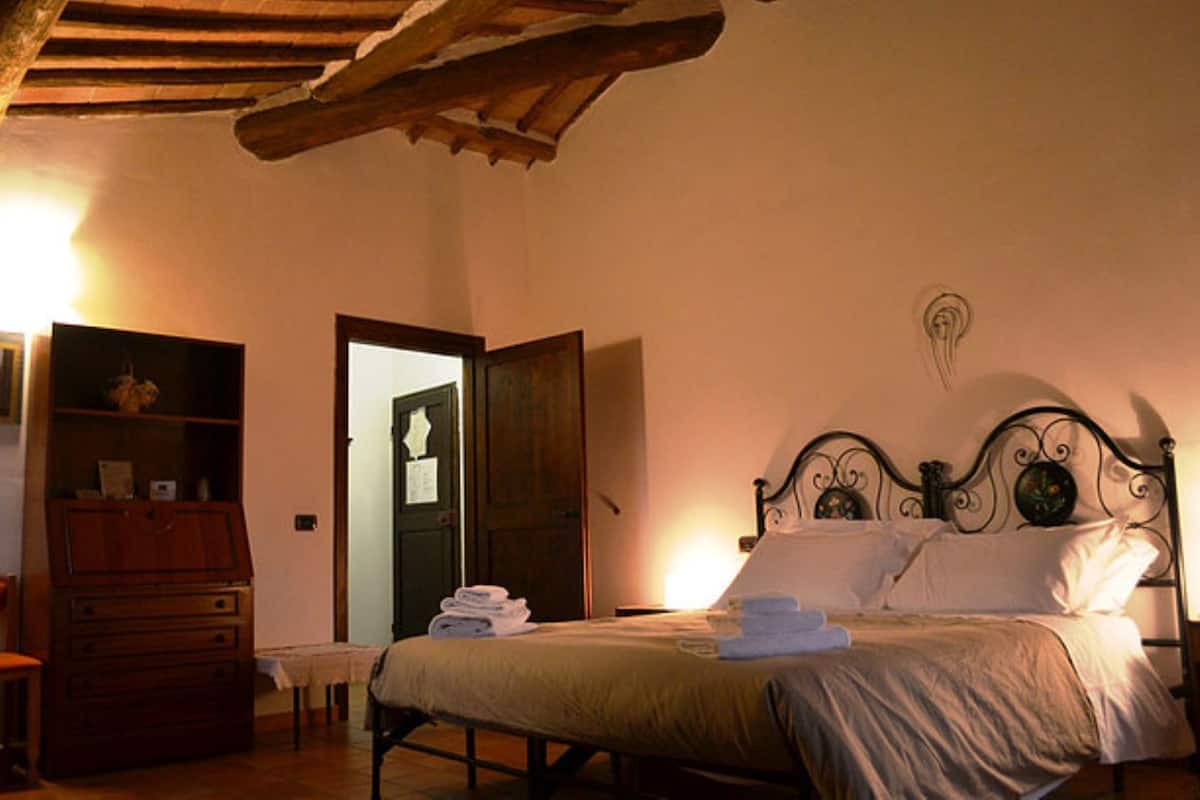 A bedroom with a bed, wooden dresser, and a door leading to another room.
