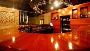 A bar area with a wooden counter, hanging light fixtures, and a display of bottles. - Best Western Premier Garden Hotel Entebbe (Entebbe)
