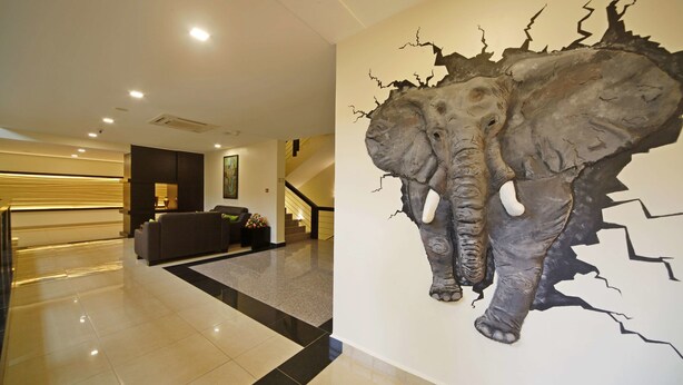 A lobby with a large elephant mural on the wall, a staircase, and a reception area with a sofa and decorative items. - Best Western Premier Garden Hotel Entebbe (Entebbe)
