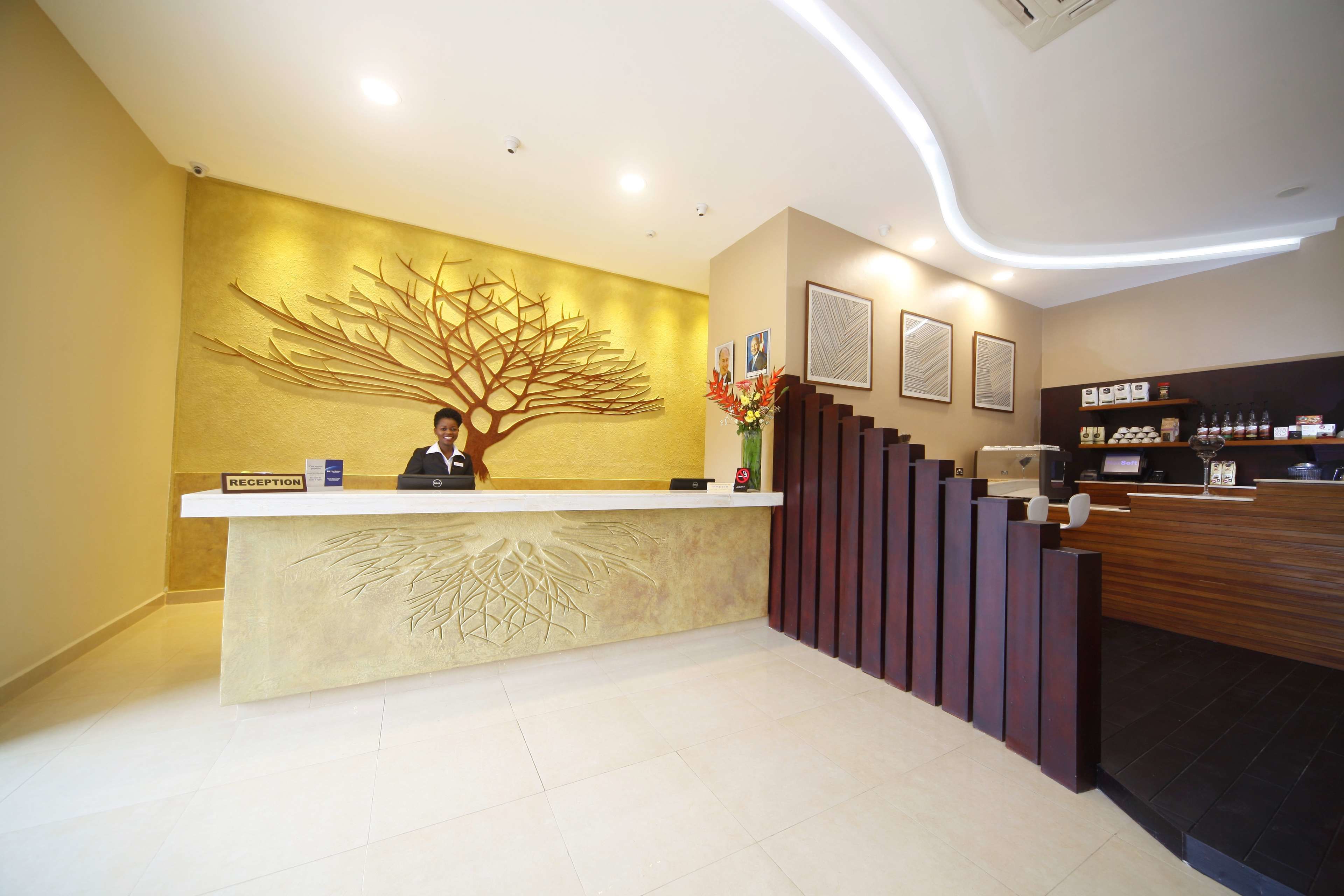 Un mostrador de recepción de diseño moderno, un mural grande con motivos de un árbol en la pared y una escalera que sube al piso superior.