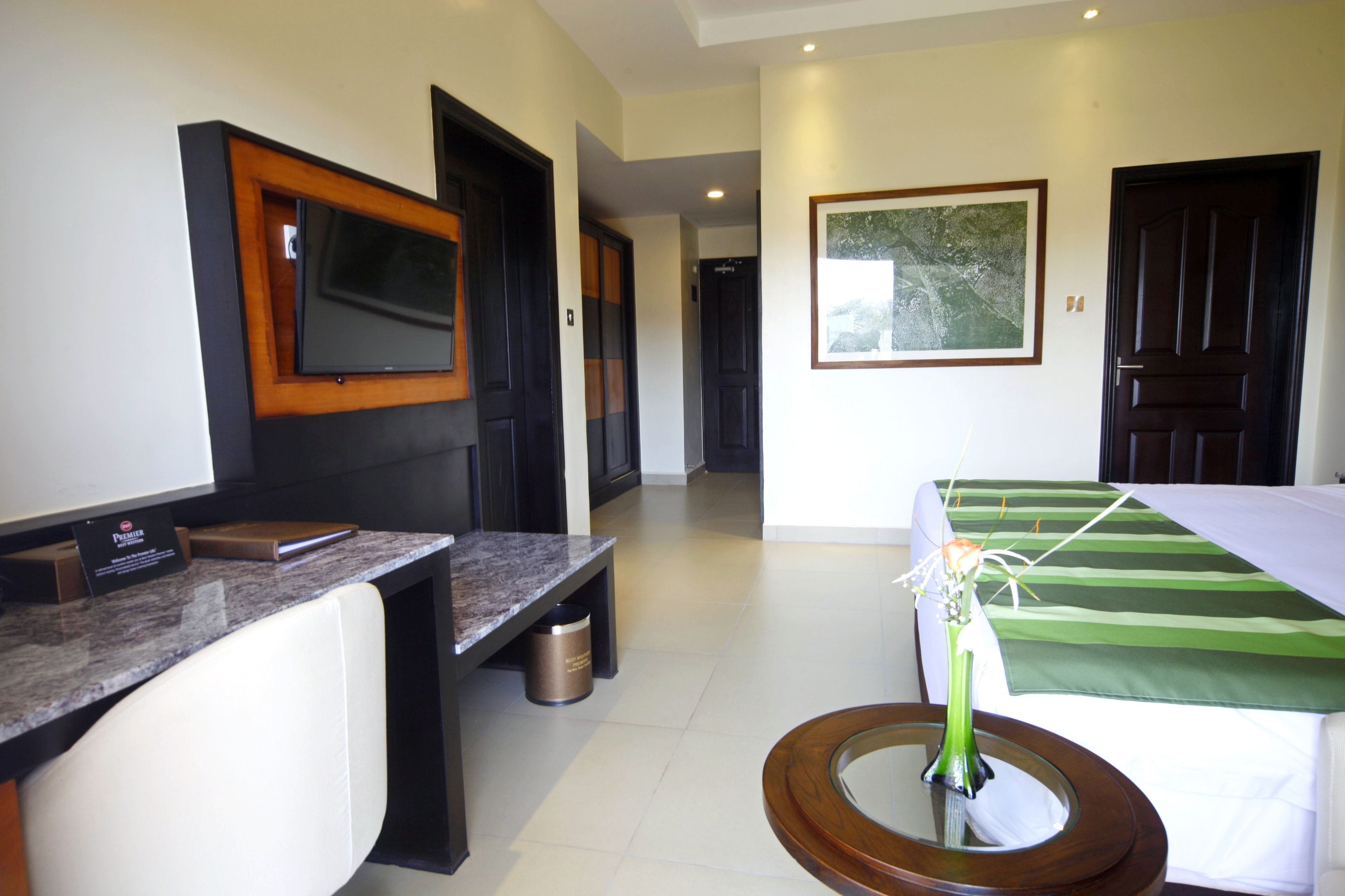 Habitación de hotel con cama, escritorio, televisor y un cuadro en la pared.
