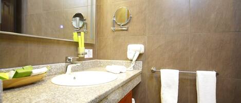 A bathroom with a granite countertop, a sink, a mirror, a towel rack, and a hand dryer.