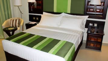 A hotel room with a bed, a chair, a nightstand, and a lamp.