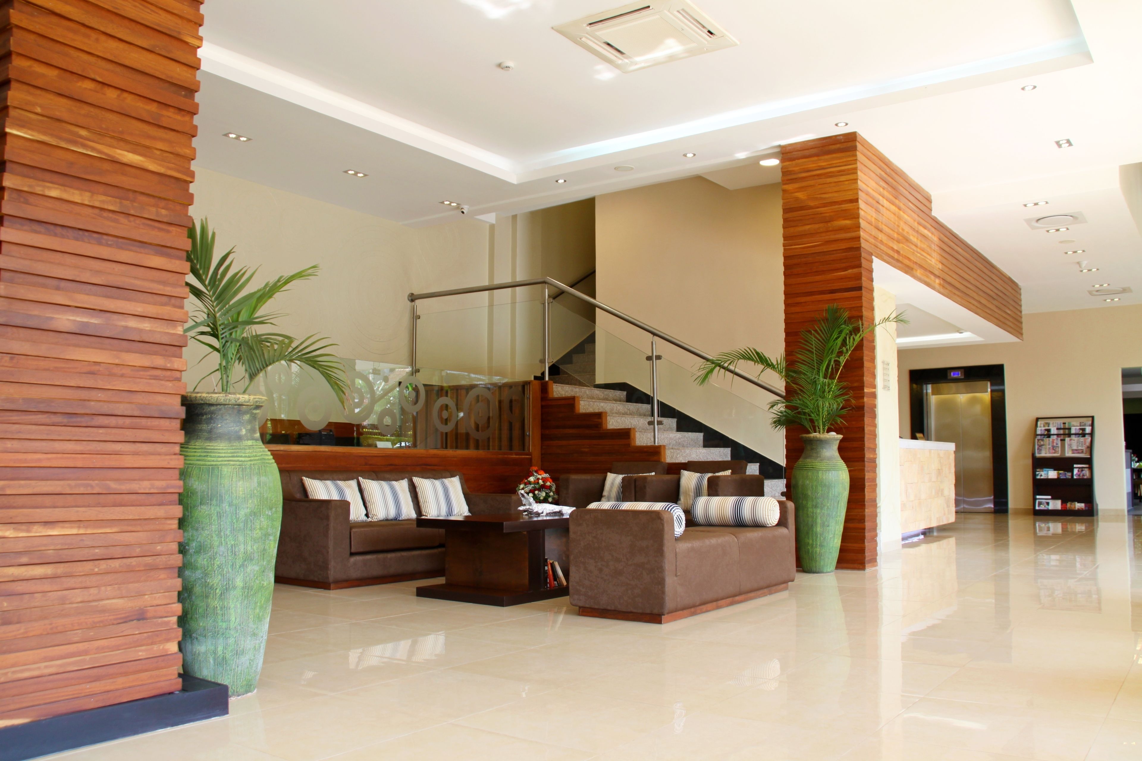 A spacious lobby with a modern staircase, a reception desk, and comfortable seating areas.