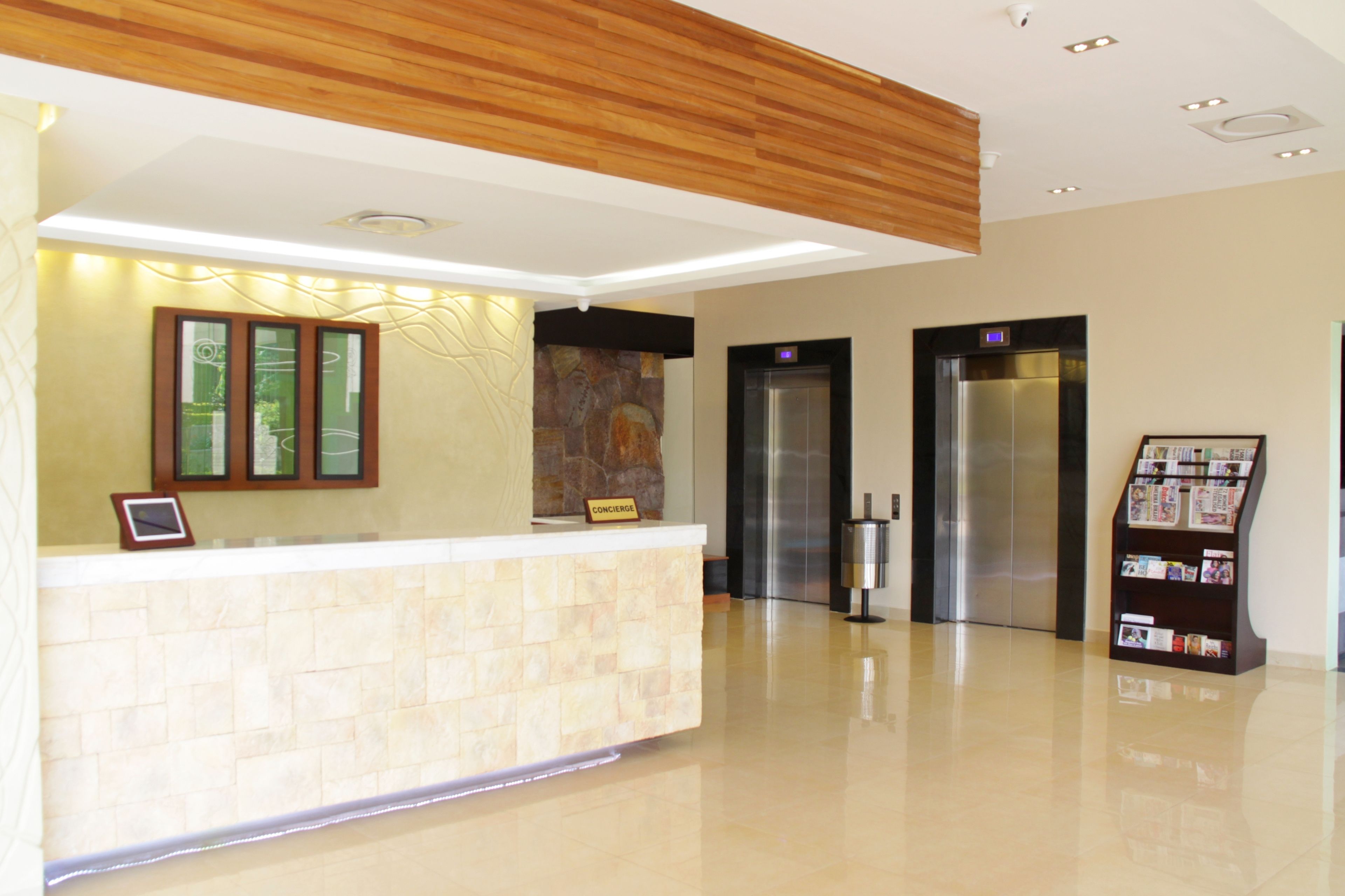 A reception area with a reception desk, two elevators, and a magazine rack.