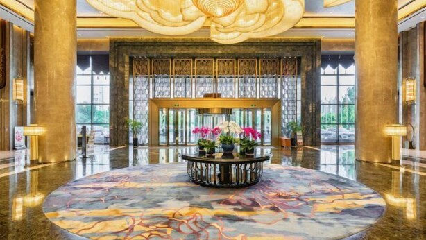 A spacious lobby with a marble floor, a central floral arrangement, and a large decorative ceiling piece. - Wanda Realm Fuyang (Fuyang)