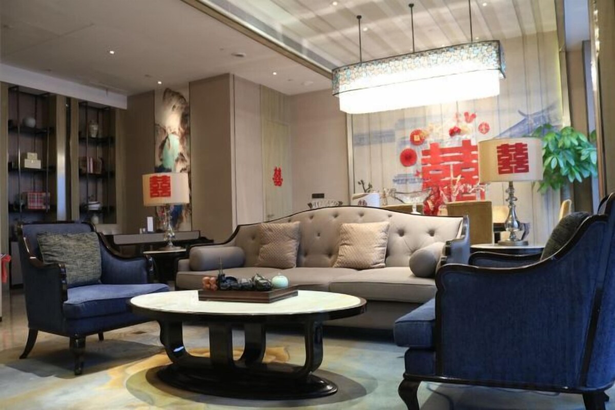 A modern living room with a sofa, armchairs, a coffee table, and a chandelier.
