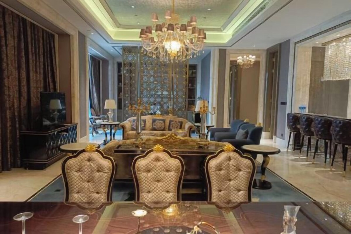 A spacious living area with a large dining table, comfortable seating, and a chandelier.