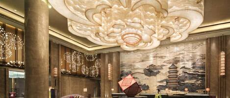 A spacious lobby with a large decorative ceiling, a traditional mural, and a central seating area.