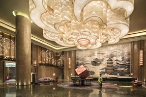 A spacious lobby with a large decorative ceiling, a traditional mural, and a central seating area. - Wanda Realm Fuyang (Fuyang)
