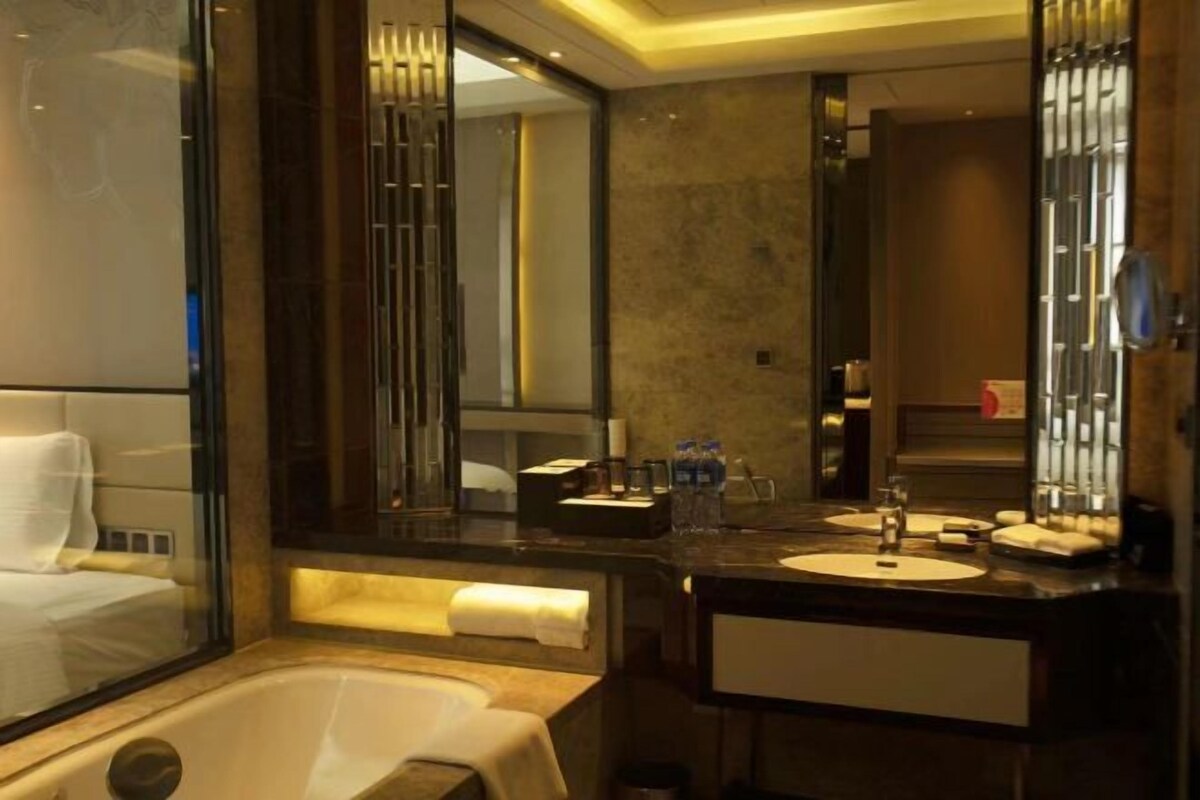 A modern bathroom with a bathtub, a large mirror, and a vanity with a sink.