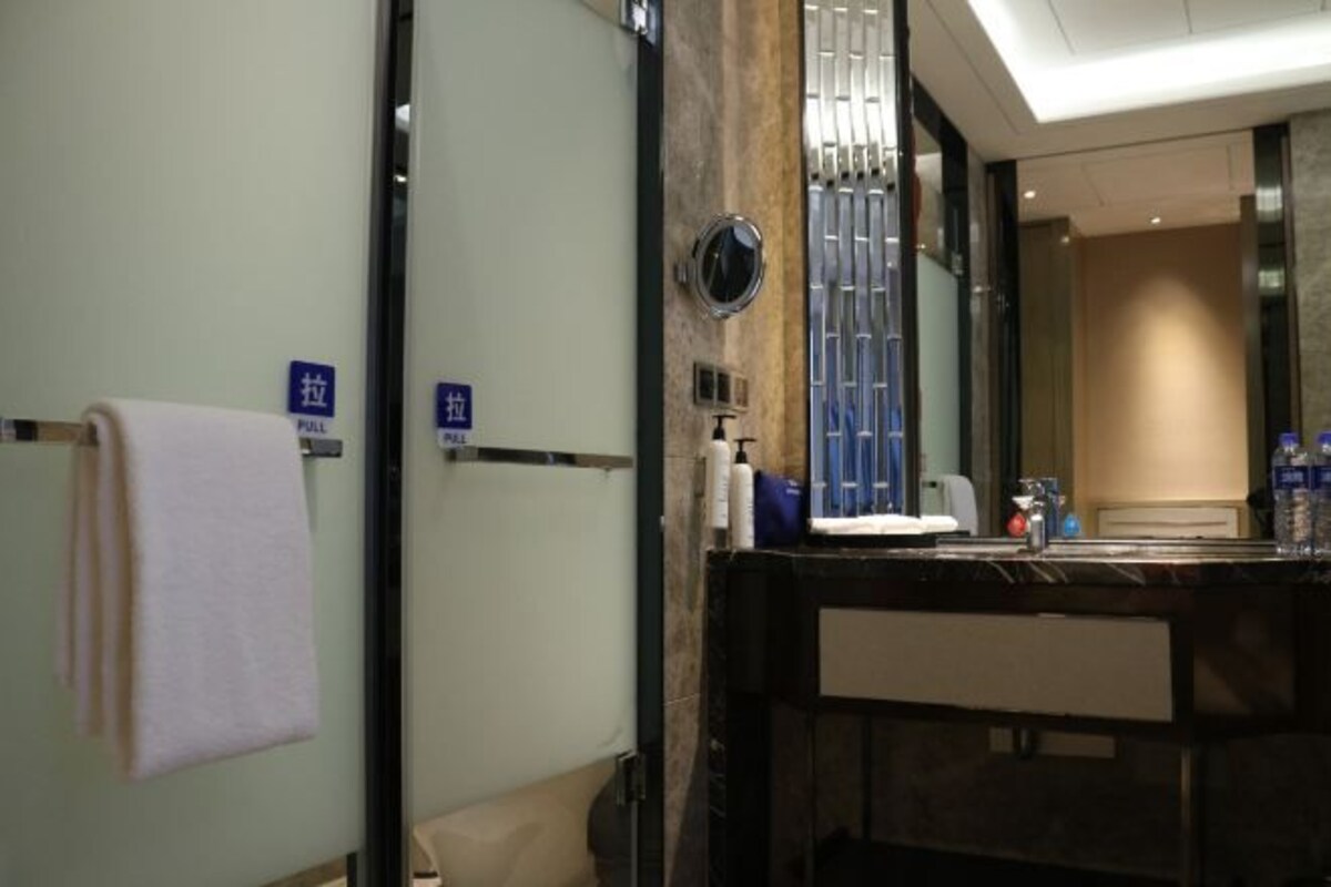 A hotel bathroom with a mirror, towel rack, and a sink.